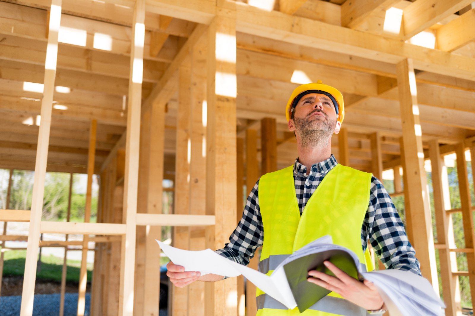Owner-builder reviewing plans at a timber-frame home under construction