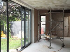 House extension under construction with scaffolding in front and rendered walls part-finished