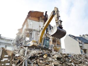 Excavator dismantling an old residential house during demolition