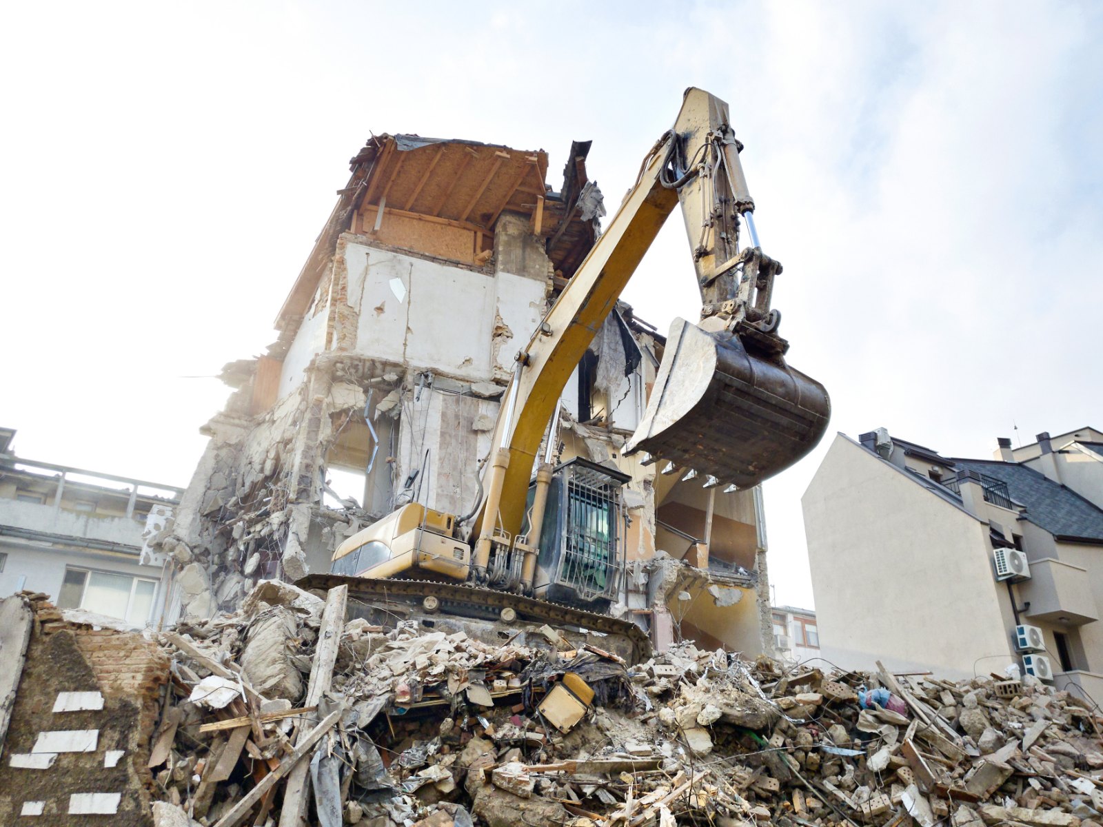Excavator dismantling an old residential house during demolition