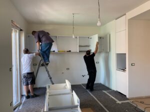 Carpenters installing cabinets and a benchtop during a kitchen renovation