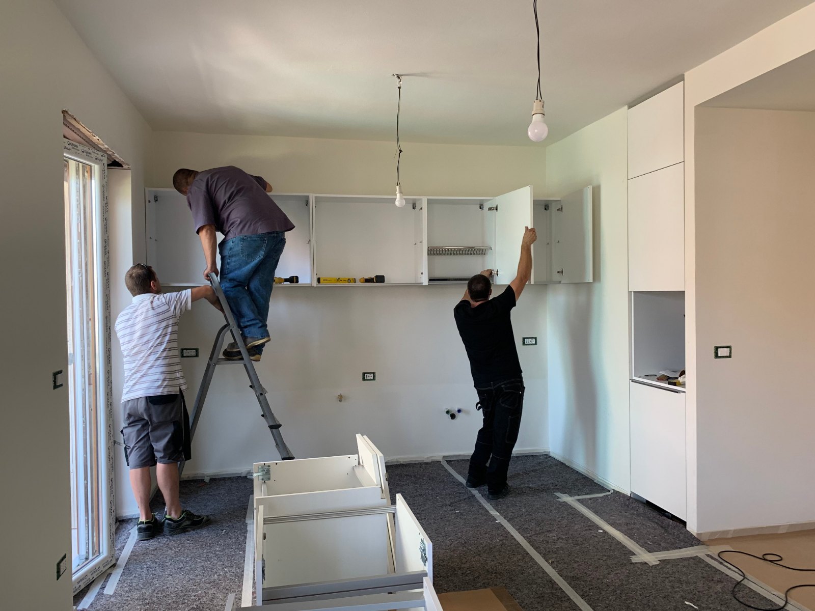 Carpenters installing cabinets and a benchtop during a kitchen renovation