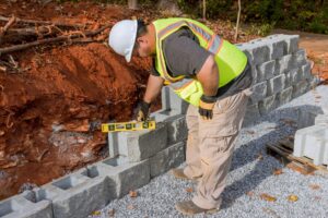 Contractor building a concrete block retaining wall on a sloping residential site